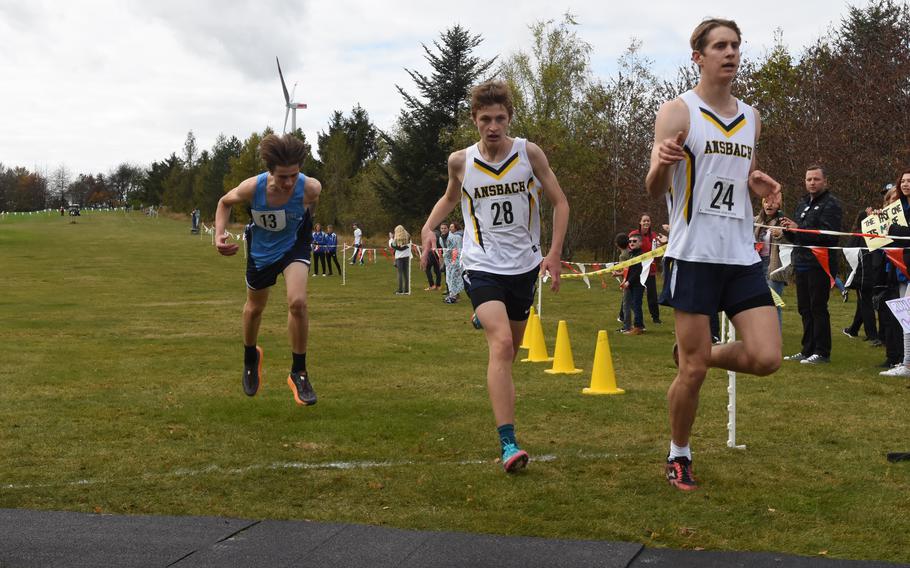 Ansbach’s Lucas Morecraft, right, finishes just ahead of teammate Brody Hocter and an outstretched Victor Kim of Black Forest Academy at the DODEA-Europe cross country championships in Baumholder, Germany, on Saturday, Oct. 23, 2021. BFA won the boys’ small schools division race while Ansbach was second.