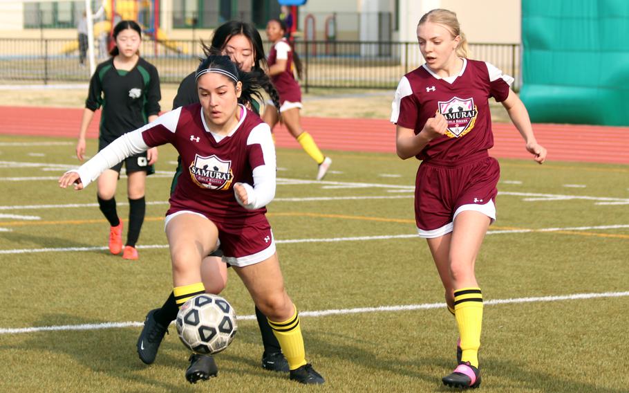 Matthew C. Perry's Elena Cerros dribbles the ball and gets an escort from teammate Cece Campbell during Friday's Western Japan Athletic Association girls soccer tournament. The Samurai won 3-1.