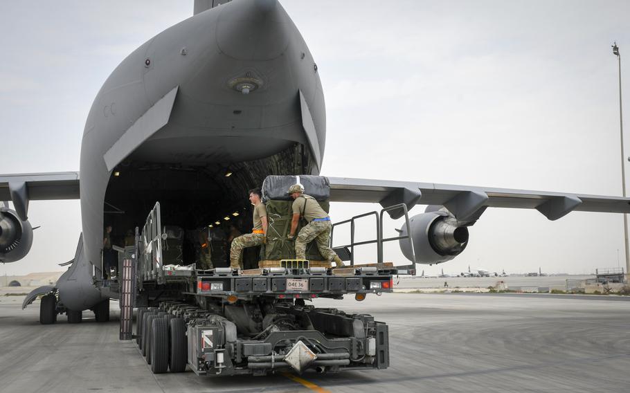 Soldiers at Al Udeid Air Base, Qatar, load a U.S. Air Force C-17 Globemaster III with a bundle of humanitarian aid on March 16, 2024. 	