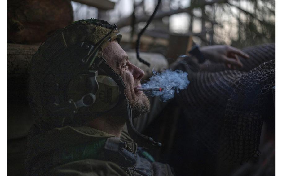 A Ukrainian serviceman from the Azov brigade, known by the call sign Chaos, smokes a cigarette while he waits for a command to fire, in a dugout about a half mile away from Russian forces on the frontline in the Donetsk region, Ukraine, on April 12, 2024. 