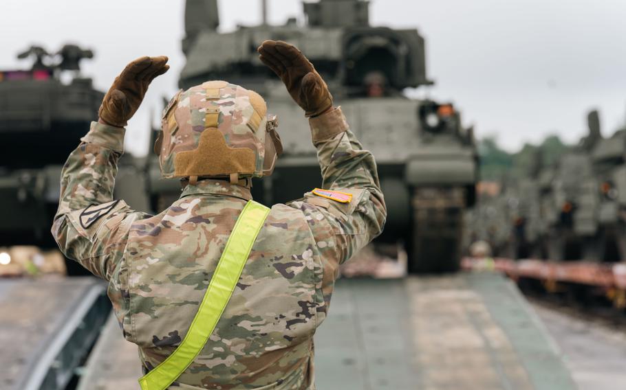 A soldier guides a tank off a rail car