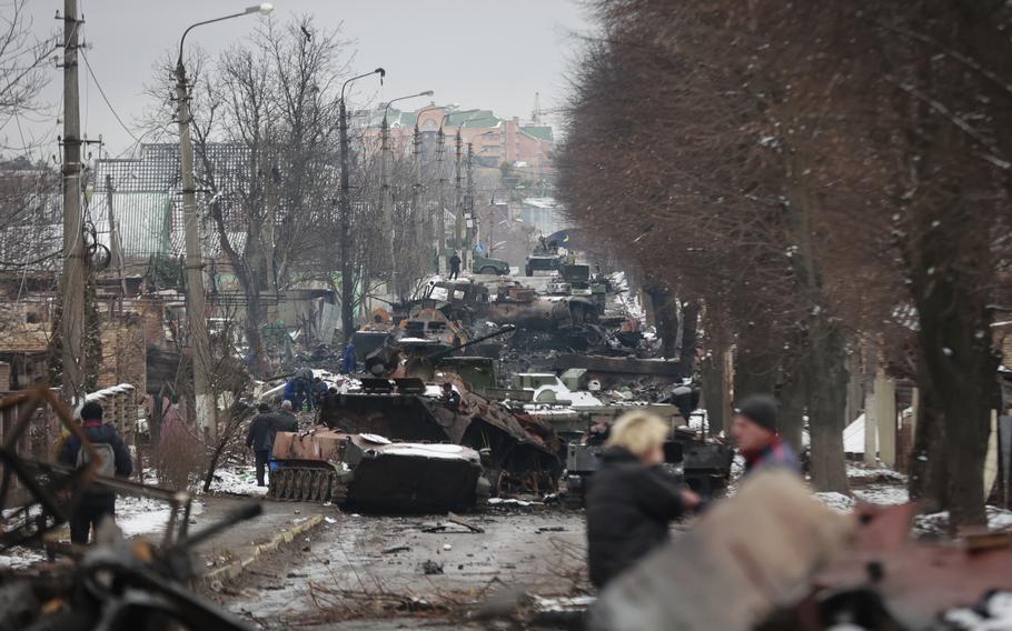 People look at the gutted remains of Russian military vehicles on a road in the town of Bucha, close to the capital Kyiv, Ukraine, Tuesday, March 1, 2022. Russian troops have surrounded Kharkiv and are closing in on Ukraine’s second-largest city two weeks after the war began, a senior U.S. defense official said Wednesday.
