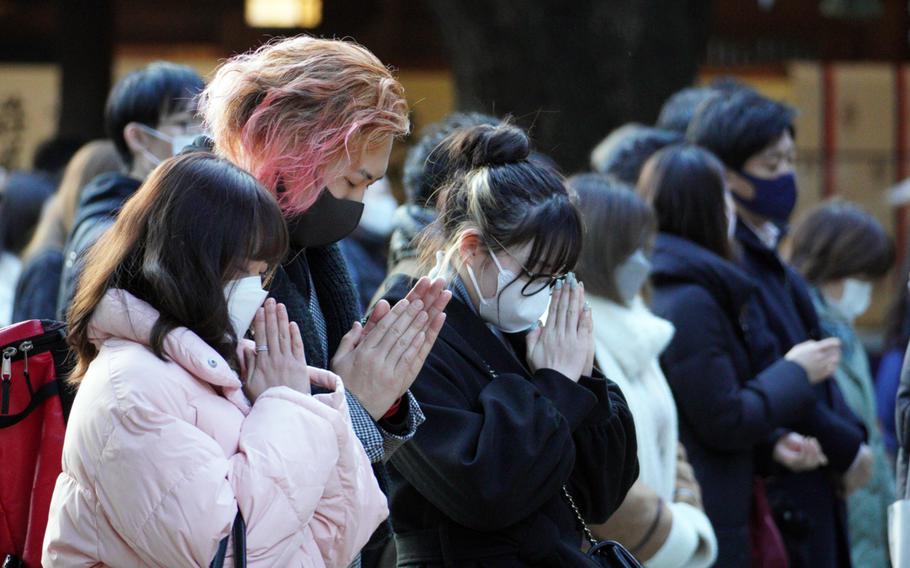 People wear masks as they pray at Meiji Jingu, a Shinto shrine in central Tokyo, Monday, Jan. 10, 2022. 