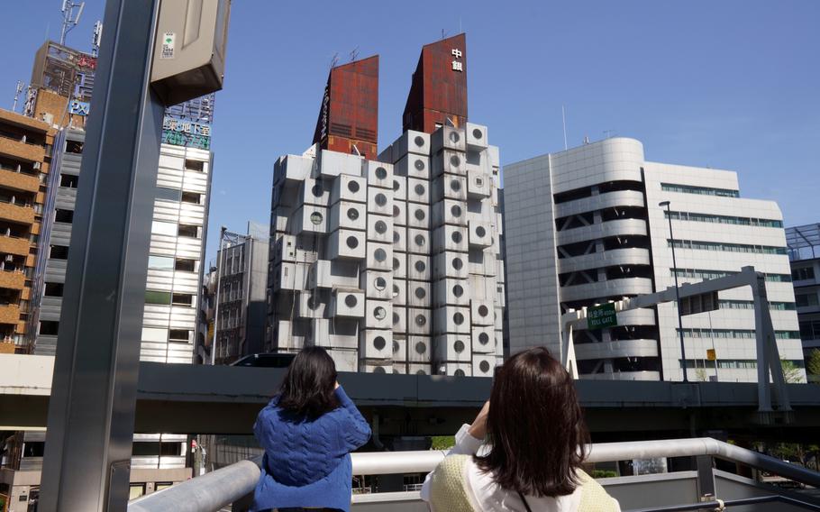 People snap photos of Nakagin Capsule Tower in Tokyo's Ginza district, Tuesday, April 12, 2022.