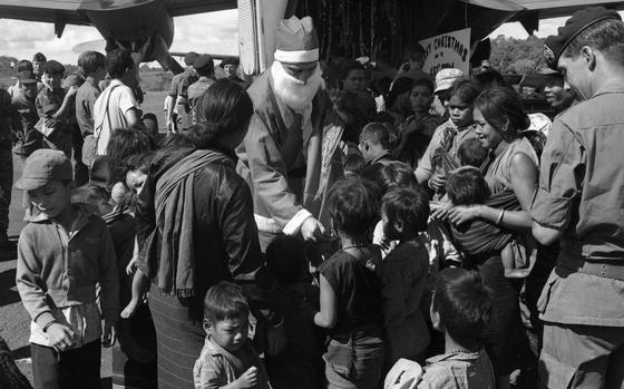 Santa Claus hands out presents to children, dependents of South Vietnamese Special Forces soldiers stationed at Nahon Cho. Some Montegnard children from the area also joined into the fun. The Air Force lent Santa six C7 Caribou cargo planes for his deliveries in Vietnam in 1968. The planes enable Santa to visit some 50 isolated outposts - such as this Special Forces camp in Nahon Cho, 80 miles northeast of Saigon - from Dec. 24th until late in the afternoon Christmas day. The planes came with the good wishes of the men of the 483rd Tactical Airlift Wing headquartered at Cam Ranh Bay.

Check out Stars and Stripes' community sites to see if Santa will visit a base near you. https://ww2.stripes.com/communities

META TAGS: Pacific; South Vietnam; holidays; Christmas; Santa Claus; children; Vietnamese; military life