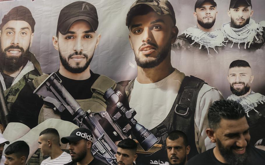 Young men stand in front of a poster of slain militants during a celebration in memory of the founders of the Lions’ Den, Mohammad al-Azizi, Aboud Suboh and Mohammad Hirzallah, in the Old City of Nablus.