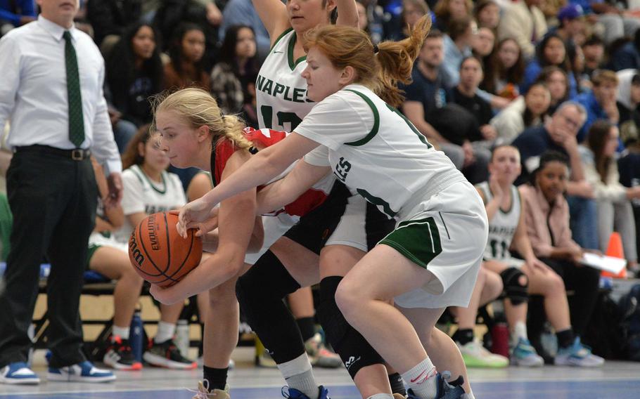 AOSRs Clara Clayton and Naples Emma Kennicott fight for the ball as Anais Navidad stands ready to help out during action in the Division II championship game at the DODEA-Europe basketball finals in Ramstein, Germany, Feb. 18, 2023. AOSR defeated Naples 26-25 to take the title.