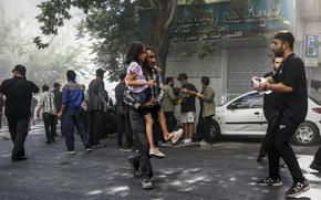 A man carries a wounded girl after an explosion in downtown Tehran.