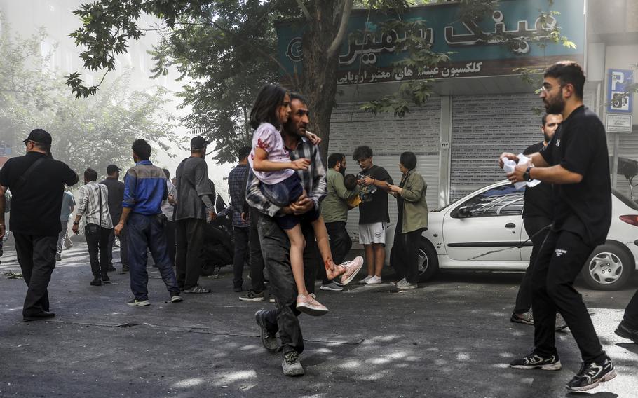 A man carries a wounded girl after an explosion in downtown Tehran.