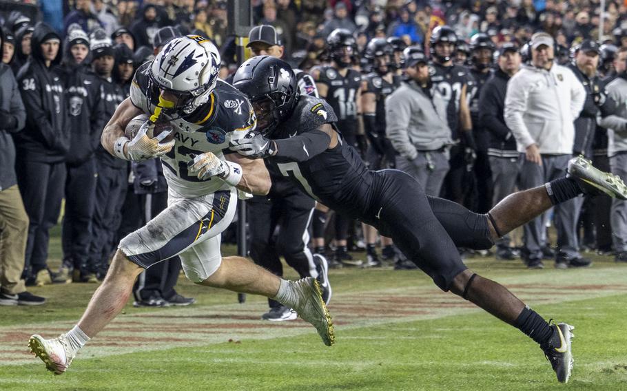 A Navy receiver tries to elude an Army defender after catching a pass.