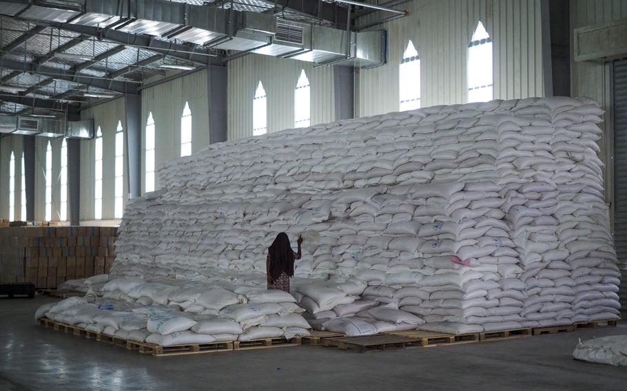 A worker walks next to a pile of sacks of food earmarked for the Tigray and Afar regions in a warehouse of the World Food Programme (WFP) in Semera, the regional capital for the Afar region, in Ethiopia on Feb. 21, 2022. The European Union said Tuesday, June 21, 2022 that Ethiopia's government must reconnect its northern Tigray region to the world as a yearlong partial blockade has left food aid for almost 1 million hungry people stuck in warehouses without the fuel to deliver it. 