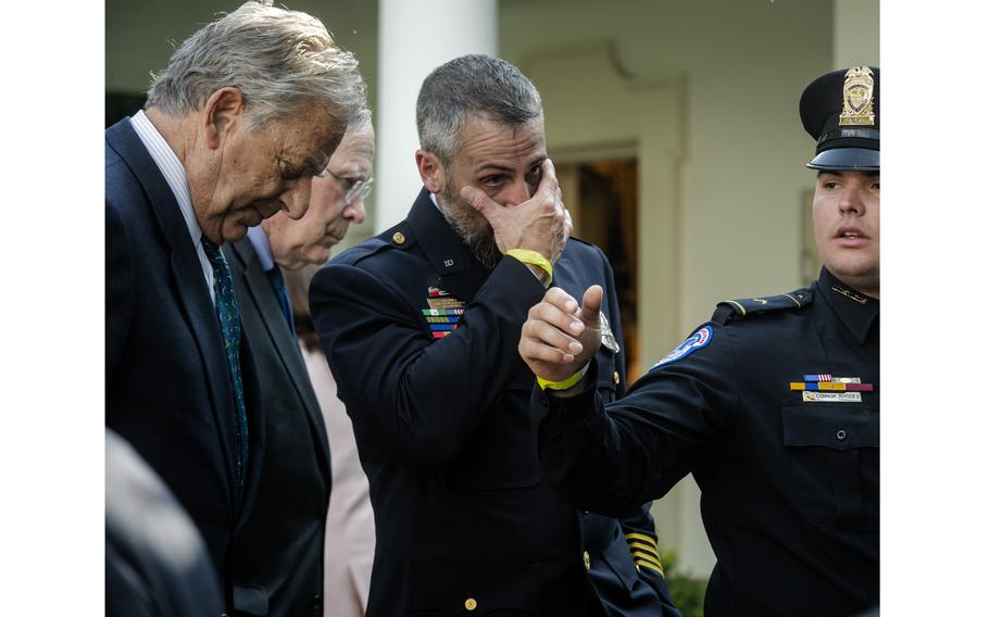 D.C. police officer Michael Fanone, center, wipes his eyes after President Biden signs an act to award the Congressional Gold Medal to officers who fought rioters at the U.S. Capitol on Jan. 6, 2021. 
