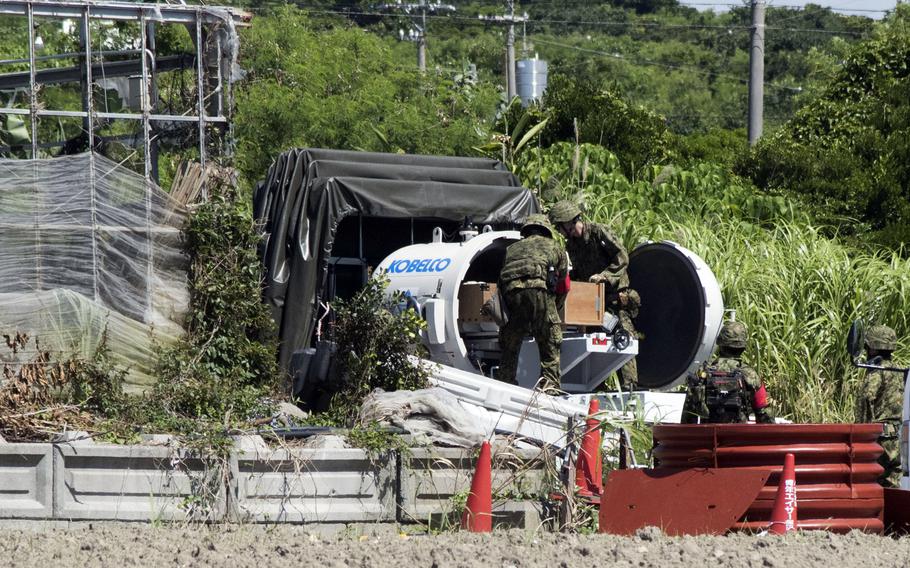 Japanese soldiers remove a U.S.-made, 5-inch shell from an explosion-proof container.