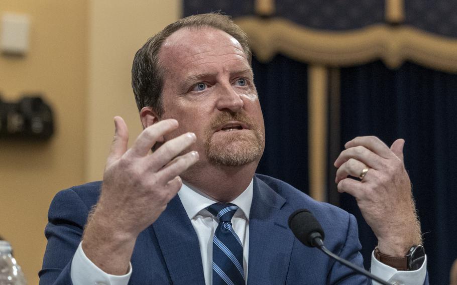 VanBemmel raises both hands during his testimony.