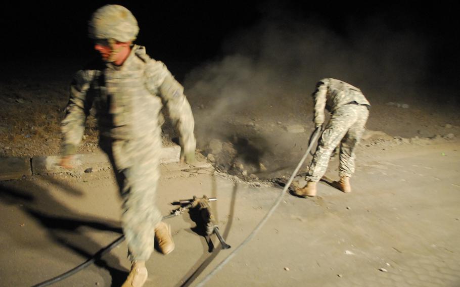 Soldiers with the 1st Platoon, 60th Engineering Company, who are attached to the 19th Engineer Battalion, prepare to fill a roadside bomb crater with concrete recently along Highway One, near Tikrit, Iraq.