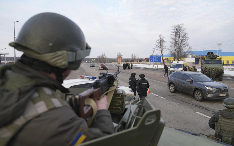 A Ukrainian National guard soldier, left, holds his weapon ready as he guards the mobile checkpoint with the Ukrainian Security Service agents and police officers in Kharkiv, Ukraine, Thursday, Feb. 17, 2022.