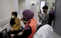 N'amah Yetzhak Abohaikal, a volunteer with the women's unit of United Hatzalah emergency service, prepares administer the COVID-19 vaccine to a teen girl as her brother and grandmother watch, at Clalit Health Services in Mevaseret Zion, Tuesday, Jan. 11, 2022. (AP Photo/Maya Alleruzzo)