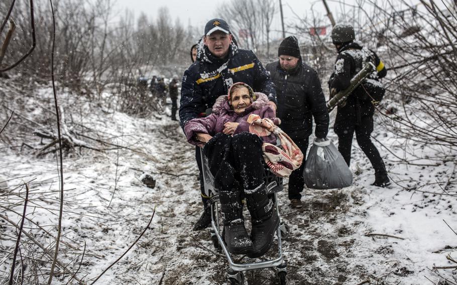 A Ukraine woman is pushed through the snow in a shopping cart as people flee the Russian advance on Irpin in March. 