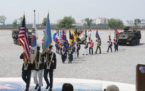 Service members carry member nation flags during a ceremony marking U.N. Command's 75th anniversary at Camp Humphreys, South Korea, July 8, 2025.