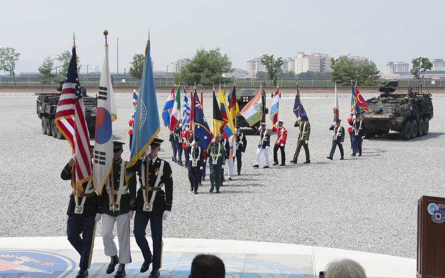 Service members carry member nation flags during a ceremony.