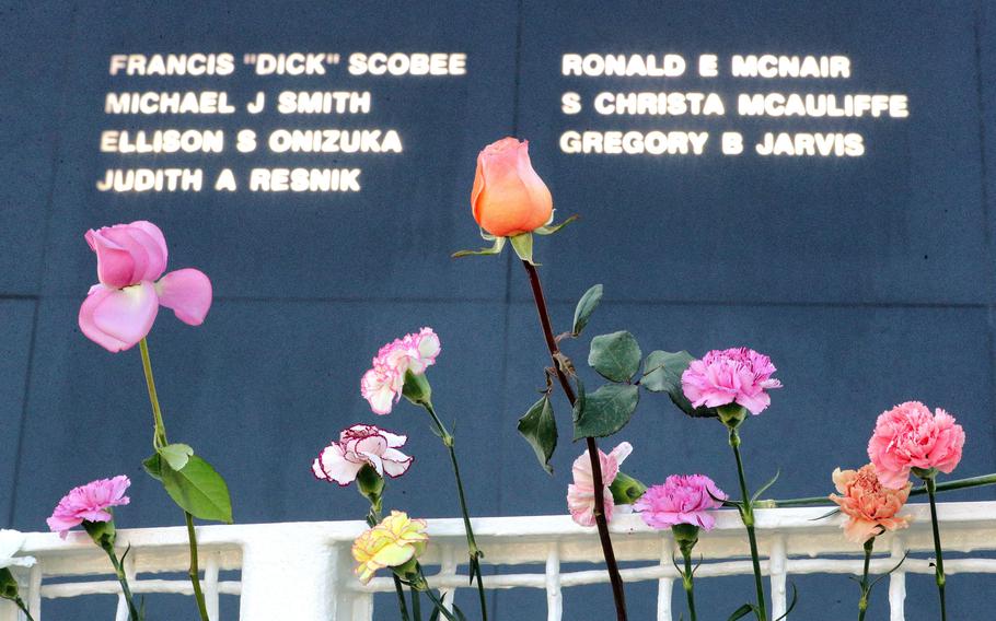 The sun illuminates the seven names of the astronauts killed in the 1986 Challenger shuttle disaster as flowers laid by guests at the base of the Space Mirror Memorial add color to the scene during a 35th anniversary commemoration ceremony at Kennedy Space Center, Fla., Thursday, January 28, 2021.