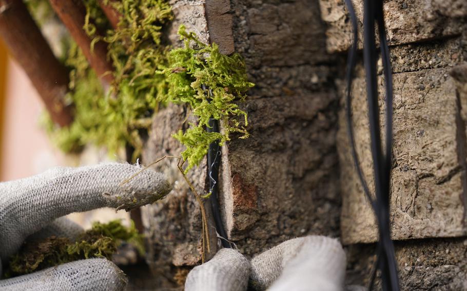 Moss is applied to a miniature bridge as part of the preparation for the annual Holiday Train Show at the New York Botanical Garden in New York, Thursday, Nov. 11, 2021. The show, which opens to the public next weekend, features model trains running through and around New York landmarks, recreated in miniature with natural materials. 