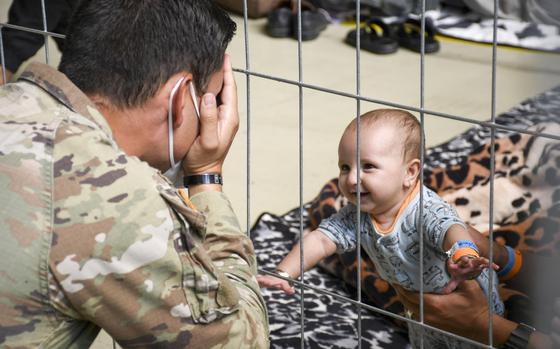 U.S. Army 1st Lt. Daniel Duncan plays with an Afghan child waiting for a flight to the U.S. in a hangar at Ramstein Air Base in Germany on Wednesday, Sept. 1, 2021.