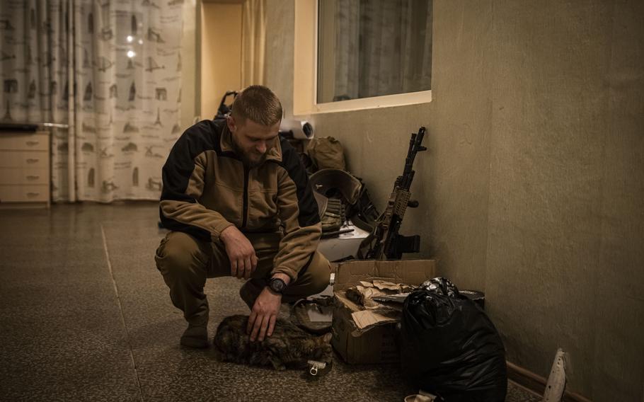 Capt. Andriy Pidlisnyy strokes a cat as it eats in the soldiers’ new base Nov. 17, 2022, in Kherson Region, Ukraine. Ukrainian troops are preparing for a long fight over winter after the Russians retreated to more fortified defensive positions on the east side of the Dnieper River. 
