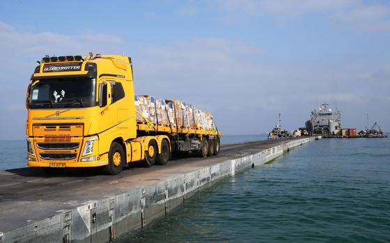 A DoD-contracted driver transports humanitarian aid from the U.S. Army vessel LSV-5, across the Trident Pier, and onto the beach in Gaza, June 20, 2024. The temporary pier, part of the Joint Logistics Over-the-Shore capability, enables the maritime delivery of international humanitarian aid to the citizens of Gaza. (U.S. Navy photo by Mass Communication Specialist 1st Class Jordan KirkJohnson)