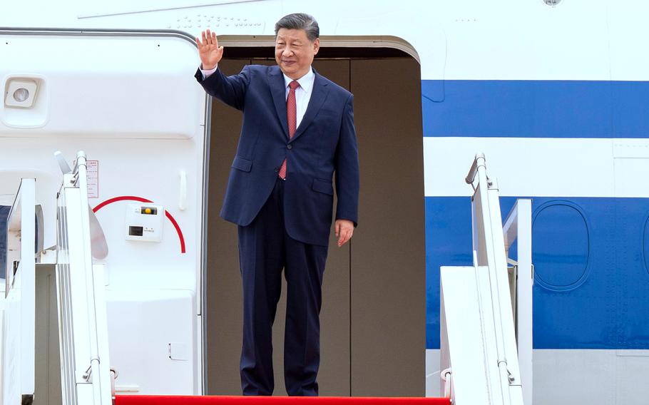 Chinese President Xi Jingping waving in front of an airplane.