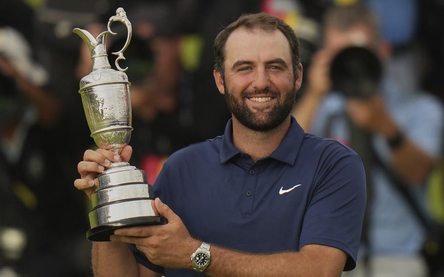 Scheffler holds the Claret Jug and flashes a big smile.