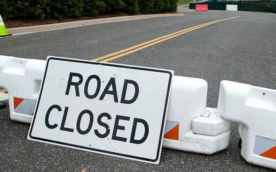 A sign reading “road closed” is propped against a traffic barrier.