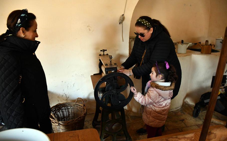 Thelma Garcia and Kelly Alvarez, show Penelope Alvarez how a mangle was used to dry clothes, at Audley End House in Essex, England.