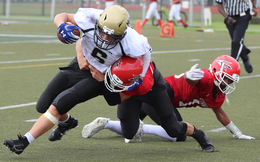 Humphreys' Luke Robinson gets wrapped up by Nile C. Kinnick defenders Joseph Maldin and Michael Torres.