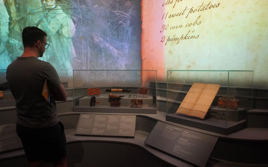 A man crosses his arms and looks at artifacts behind a display case