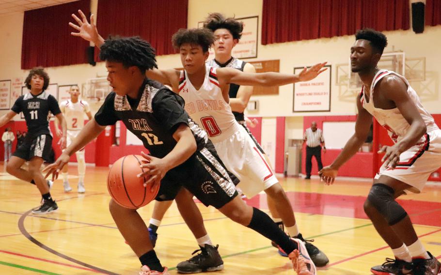 Zama's Casey Stewart triies to dribble free of Nile C. Kinnick's Arashi Blocton and Kennedy Hamilton during Tuesday's DODEA-Japan boys basketball game. The Red Devils won 71-38.