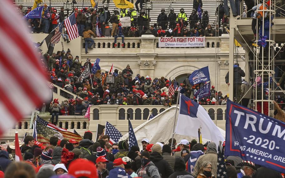 A throng of people take over the inaugural stage at the U.S. Capitol in Washington on Jan. 6, 2021, as police look on.