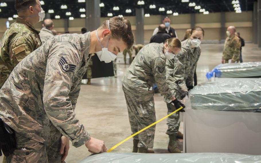 Staff Sgt. Sean Ofiara (left), 103rd Logistics Readiness Squadron, measures spacing between field hospital beds at the Connecticut Convention Center in Hartford on April 11, 2020. Soldiers and airmen from the Connecticut National Guard were setting up more than 600 beds at the site as potential hospital surge capacity for patients recovering from the coronavirus.