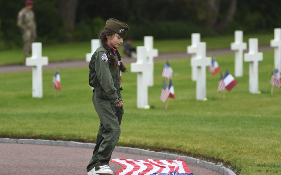 A young girl looks at the American flag at the Normandy American Cemetery during a ceremony marking the 79th anniversary of the D-Day invasion, Tuesday, June 6, 2023.