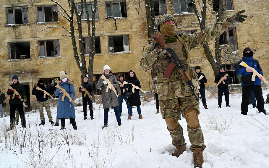 A military instructor teaches civilians holding wooden replicas of Kalashnikov rifles, during a training session at an abandoned factory in the Ukrainian capital of Kyiv on Jan. 30, 2022.