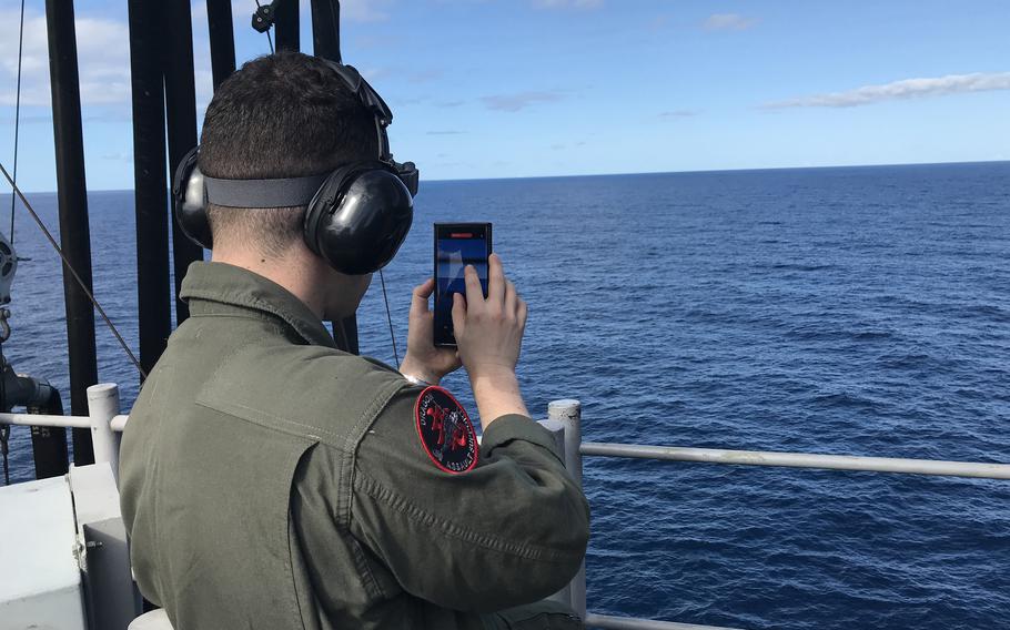 A Marine films whales breaching near the USS America amphibious assault ship in the Coral Sea, Monday, July 31, 2023.