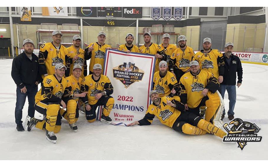 Members of the Pittsburgh Warriors hockey team hold a banner declaring them champions of the 2022 Disabled Hockey Festival.