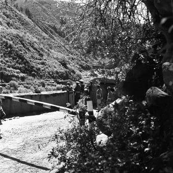 A black and white photo of security personnel leaning on a balcony, looking out at a hill or valley.