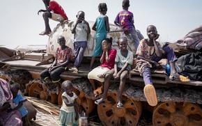 Children sit and play on the remains of a tank, at the river port in Renk, South Sudan Wednesday, May 17, 2023. Tens of thousands of South Sudanese are flocking home from neighboring Sudan, which erupted in violence last month. (AP Photo/Sam Mednick)
