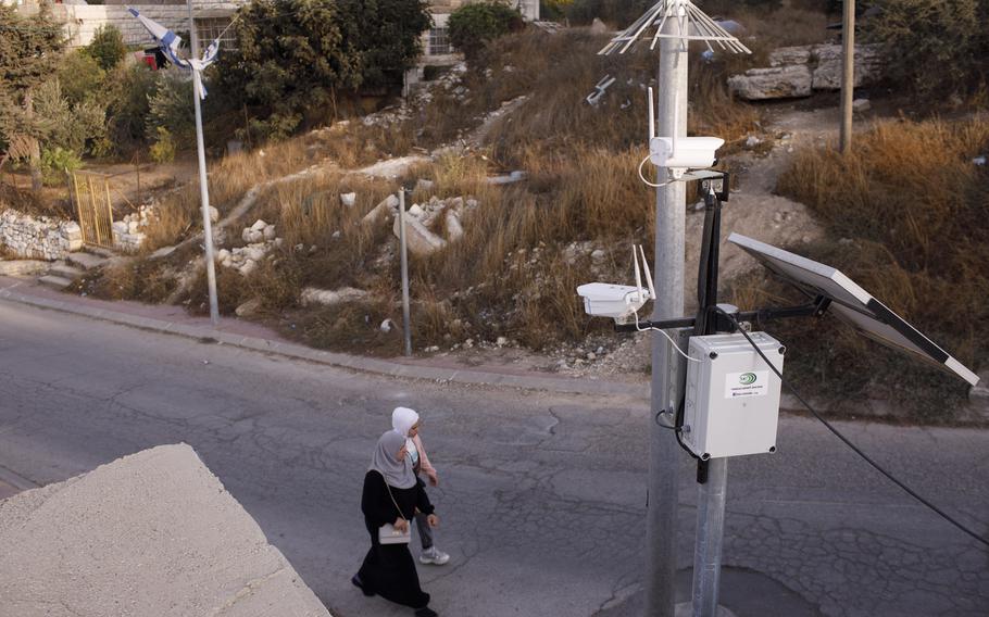 Cameras used by Jewish settlers watch Palestinian pedestrians on a street in Hebron. 