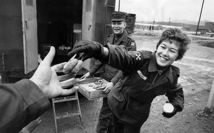 A woman hands out donuts to a service member
