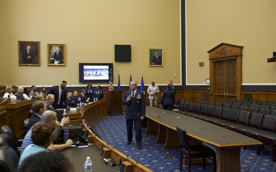 Guests sitting down while a ranking Airman speaks through a microphone.