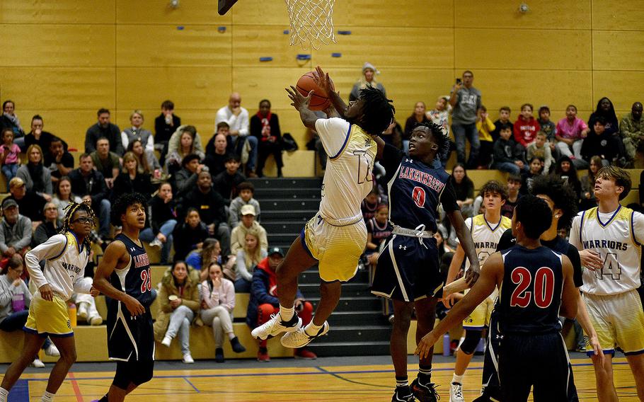 Warrior Zion Thompson goes up on a drive while Lakenheath's Gideon Toure goes up to block the shot during a Dec. 1, 2023, game at Wiesbaden High School in Wiesbaden, Germany.