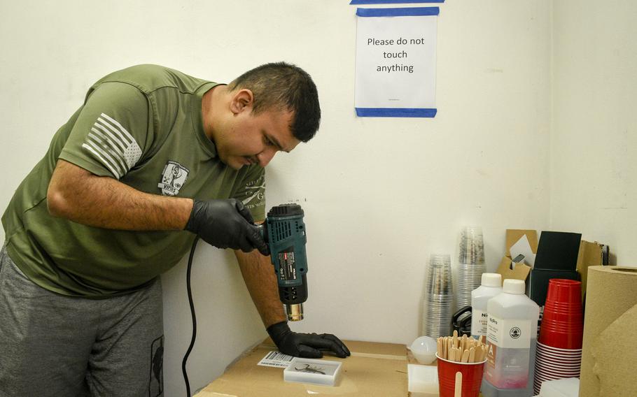 Air Force Staff Sgt. Adan Guzman aims a heat gun at a resin cast of a scorpion captured on a hunt at Ali Al Salem Air Base in Kuwait. The scorpions are given out as mementos of the deployment.