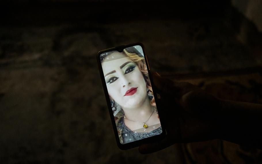 A photo of Hind Latif al-Khadir is shown on a cellphone by her sister at their home in Dashisha.